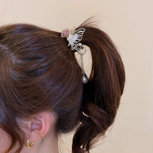 Detail of floral hair claw with rhinestones, pink rose and pearl tassel on hair