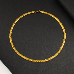 Detailed macro view of flat gold cuban link necklace on a textured black background