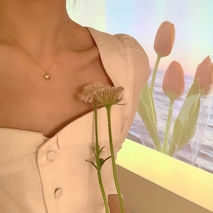 Minimalist 3D heart pendant necklace in gold finish worn by a model in warm light