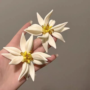 Macro detail of white floral earrings with amber bead center and silver needle design