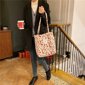 Detalle de bolso tote de pana con flores, etiqueta blanca cosida y textura suave de algodón