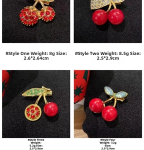 Detail view of four cherry brooches with red crystals and sizes on black fabric