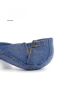 Detail of blue denim beret with vintage brass metal buckle and orange stitching