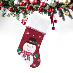 Detail of red Christmas stocking with snowman embroidery hanging on festive pine branches