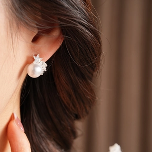 Gros plan d'élégantes boucles d'oreilles en argent avec étoile et perle sur l'oreille