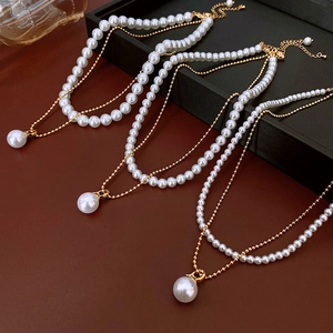 Détail du collier double rang en or avec pendentif perle blanche et chaîne d'extension