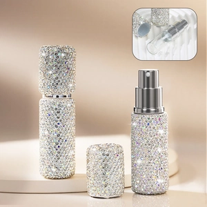 Detailed view of rhinestone-studded portable perfume bottle with nozzle and silver cap