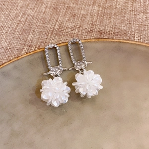 Elegant silver flower tassel earrings with crystals and white petals on linen background