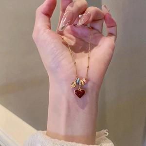 Detail of 18k gold plated necklace featuring a red heart pendant and colorful beads