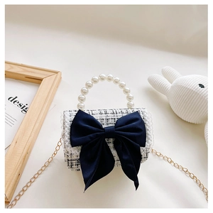 Detail of tweed mini crossbody bag with pearl handle and large navy blue bow