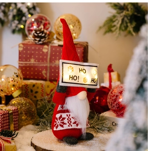 Close-up of red Christmas gnome with a glowing HO HO HO banner and snowflake knit hat
