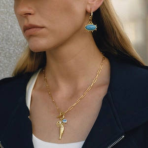 Detail view of model wearing gold paperclip chain necklace and evil eye hoop earrings