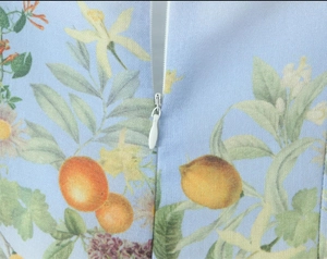 Detail of invisible zipper on bohemian light blue dress with tropical fruit floral print