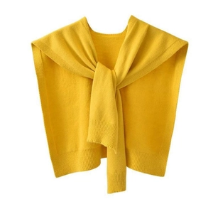 Detail of soft yellow knitted shawl wrap with textured ribbing and decorative front knot
