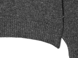 Close-up of charcoal grey knit top featuring ribbed hem and side slit details