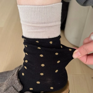 Detail of yellow polka dot socks and beige ribbed knit socks showing stretch and texture