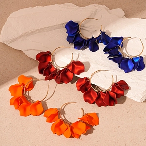 Three pairs of vintage acrylic flower petal hoop earrings in blue, red, and orange