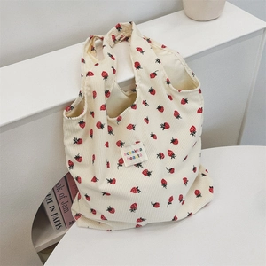 Détail du sac cabas en velours côtelé à motif fraise sur support minimaliste