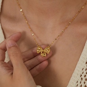 Golden bow pendant necklace in polished stainless steel for women on a model neck