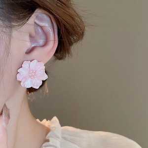 Close-up of pink flower earrings with resin petals and white pearl stamen on ear