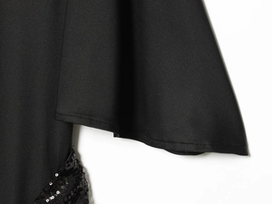 Detail of black midi dress showing sequin texture and wide flared sleeve design