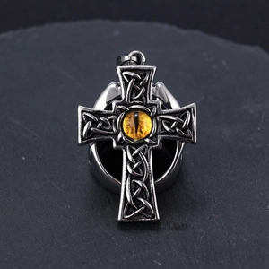 Macro detail of gothic Celtic knot cross pendant with central yellow dragon eye stone