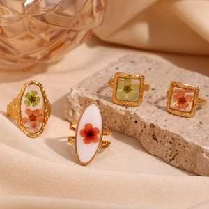 Detailed macro view of 18K gold-plated rings with dried flowers in transparent resin