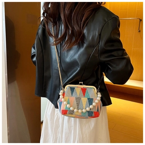 Detailed shot of a geometric multi-color shell bag with pearl handle and metal clasp