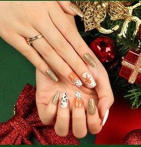 Detail of Christmas press-on nails with gingerbread man and gold glitter on long coffin shape