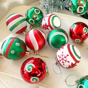 Close-up of red and green glittery Christmas ornaments with snow patterns in a white tray
