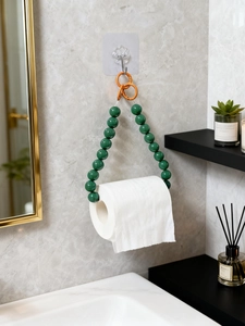 Detail of green beaded toilet paper holder with orange rings against marble wall