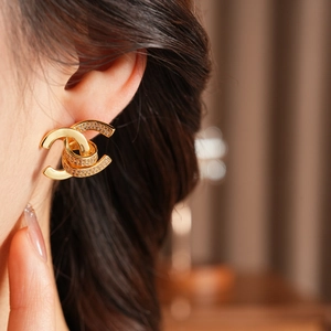 Macro shot of 18k gold plated double-C earrings with pavé crystals on ear