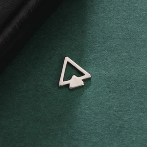 Macro shot of silver arrow pendant in polished stainless steel on a dark green surface