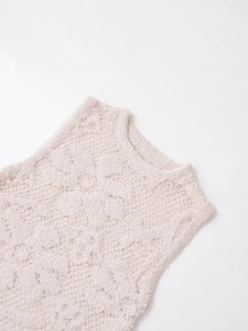 Gros plan sur la texture en maille pelucheuse et le col rond d'un gilet rose doux
