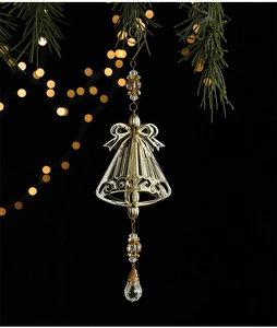 Detailed view of golden Christmas bell ornament with crystal beads on pine branch