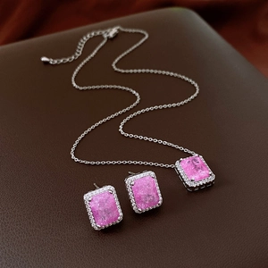 Detail of silver jewelry set featuring rectangular pink crystal pendants with zircon stones
