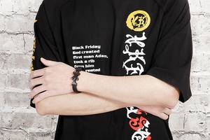 Detail of black woven leather anchor bracelet with decorative cross on male model