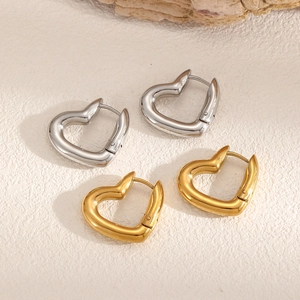 Minimalist gold and silver heart hoop earrings set on stone background in warm light