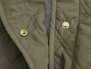 Détail de la veste matelassée vert armée avec boutons-pression en métal doré chic