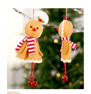 Detail of gingerbread man felt ornament with bells hanging on a snowy Christmas tree branch