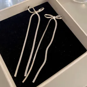 Silver bow-knot long tassel earrings made of snake chain displayed in a jewelry box