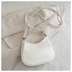 Close-up of white faux leather crescent shoulder bag on a minimalist beige blazer background