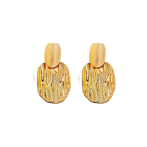 Exaggerated golden geometric earrings with textured metallic finish on a white background