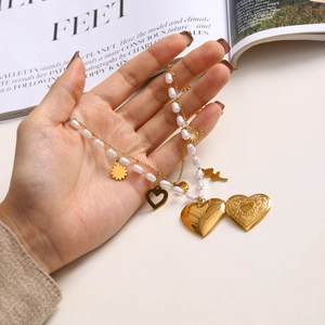 Détail d'un collier en acier inoxydable doré avec perle blanche et charms cœur