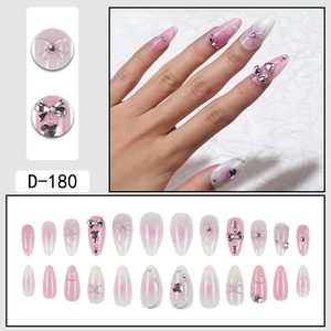 Pink gradient press-on nails with 3D bows, rhinestones, and pearls on white cloth
