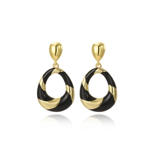 Close-up of elegant black oil-dripped oval earrings with vintage golden twisted texture