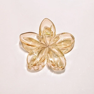 Detailed view of amber acrylic plumeria hair claw clip with golden metal spring