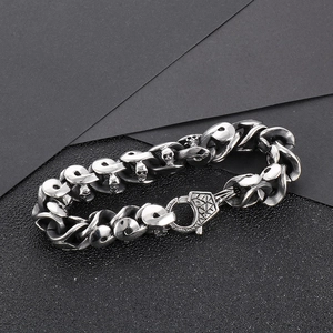 Bracelet punk en acier inoxydable pour homme avec breloques crâne sur fond texturé gris