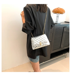 Close-up of quilted silver crossbody bag with gold chain strap and metallic lock clasp