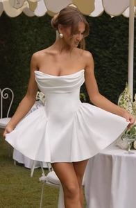 Detailed close-up of white strapless satin mini dress with elegant ruched texture and volume